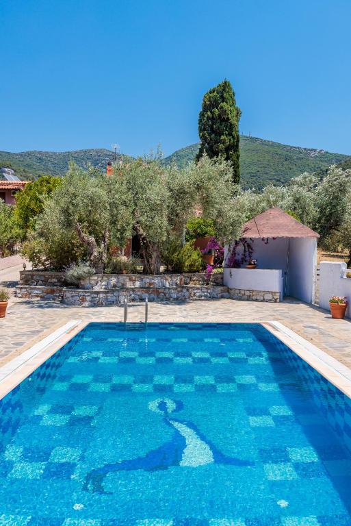 a large swimming pool with blue water in a yard at Aretousa - Deluxe Pool Apartment in Skopelos Town