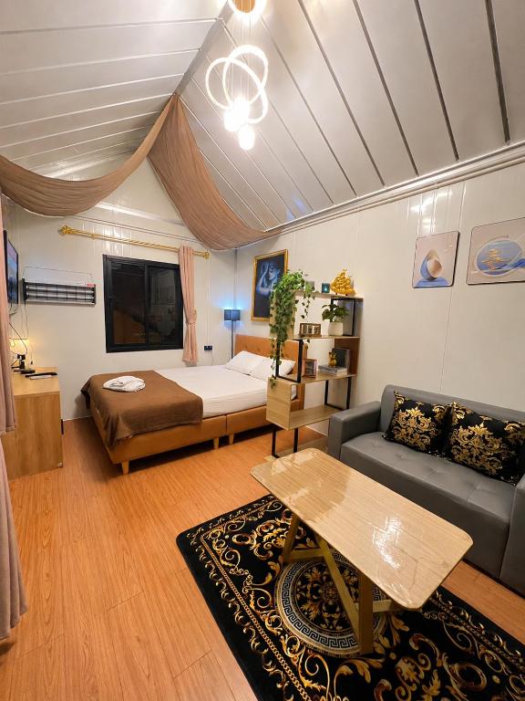 a bedroom with a bed and a couch and a table at NearBKKHomestayAirport in Bang Phli