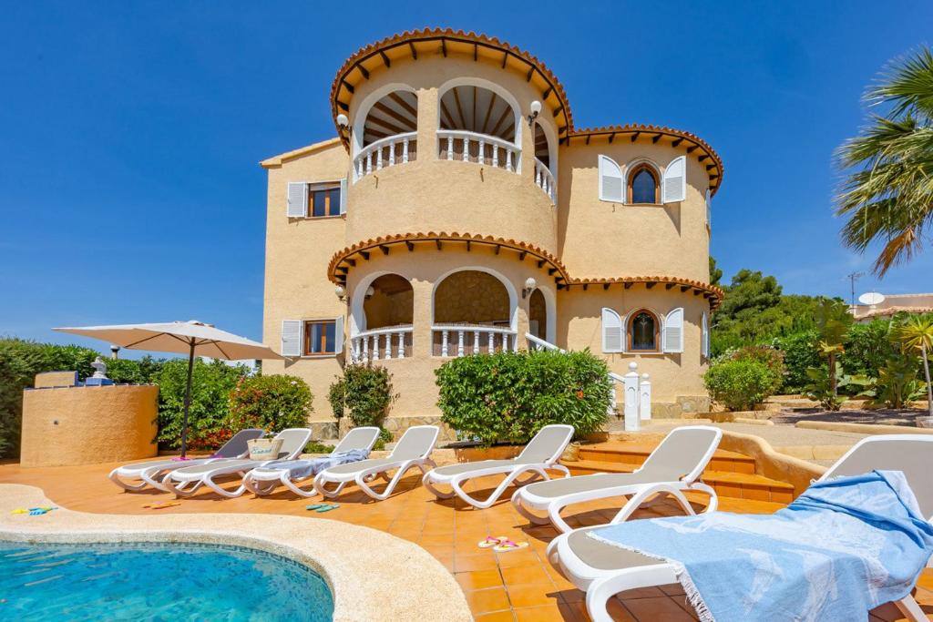 a building with chairs and a pool in front of it at Villa Ortembach- PlusHolidays in Ifach