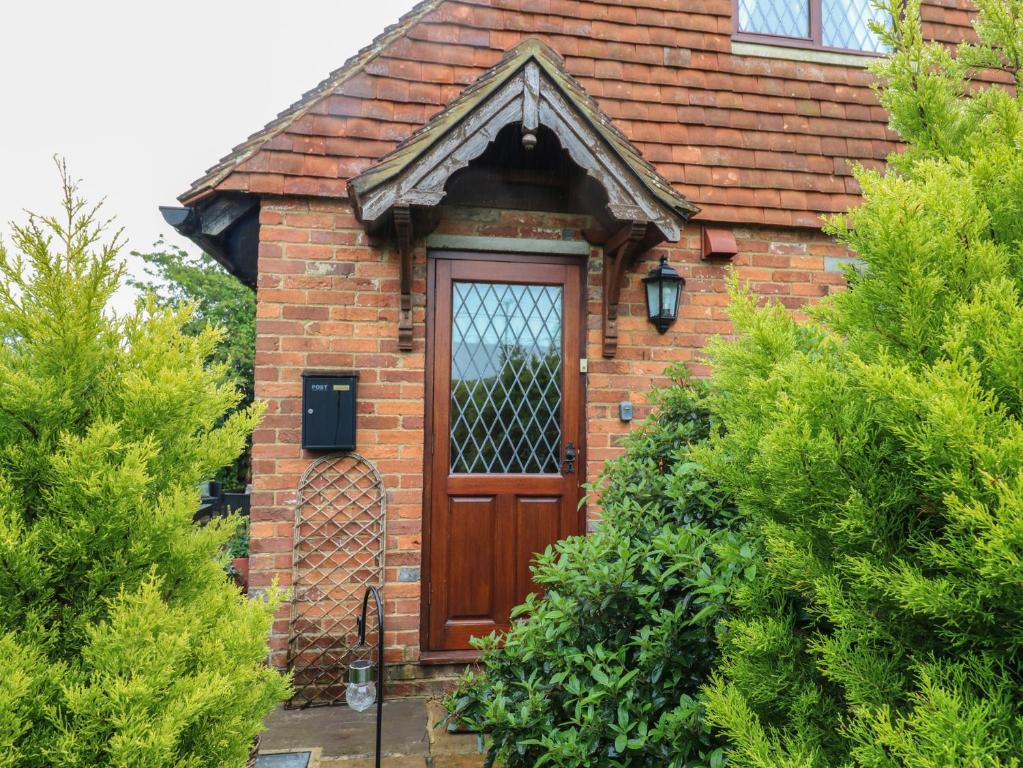 a red brick house with a wooden door at Barclay Cottage in Ashford