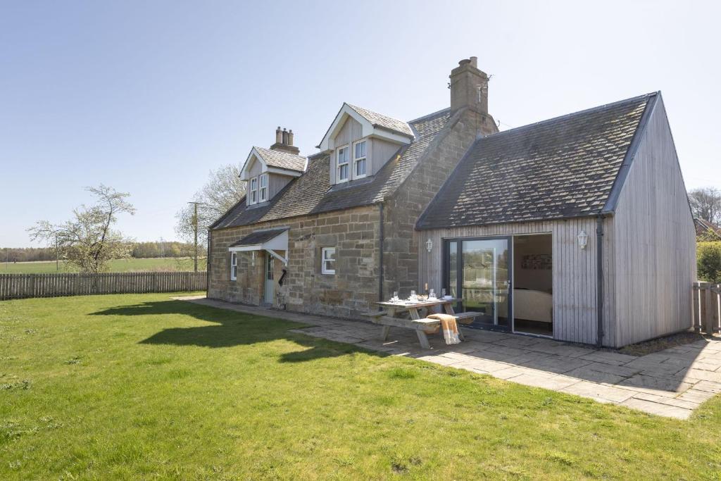 an old stone house with a table in a yard at Coldwells Farmhouse in Dalkeith