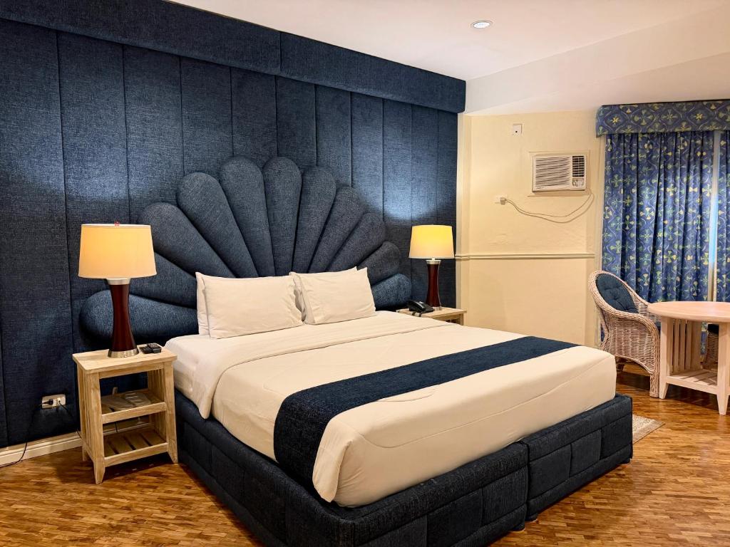 ein Schlafzimmer mit einem großen Bett mit großem Kopfteil in der Unterkunft Coco Grande Hotel in Dumaguete