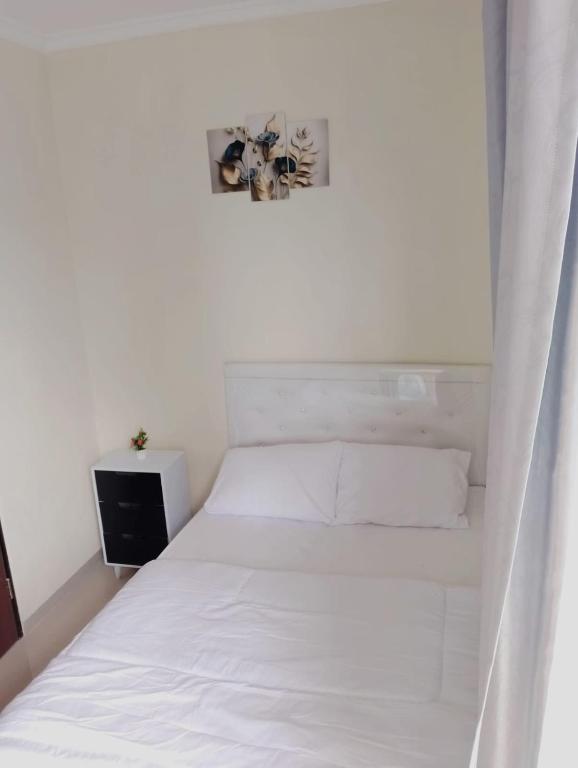 a white bed in a white room with a window at A-Three Guest House in Malang