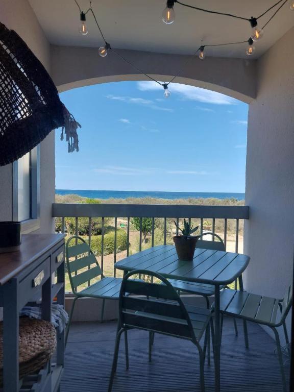 a blue table and chairs in a room with a balcony at Studio cabine, vue mer, piscine in Saint-Cyprien-Plage