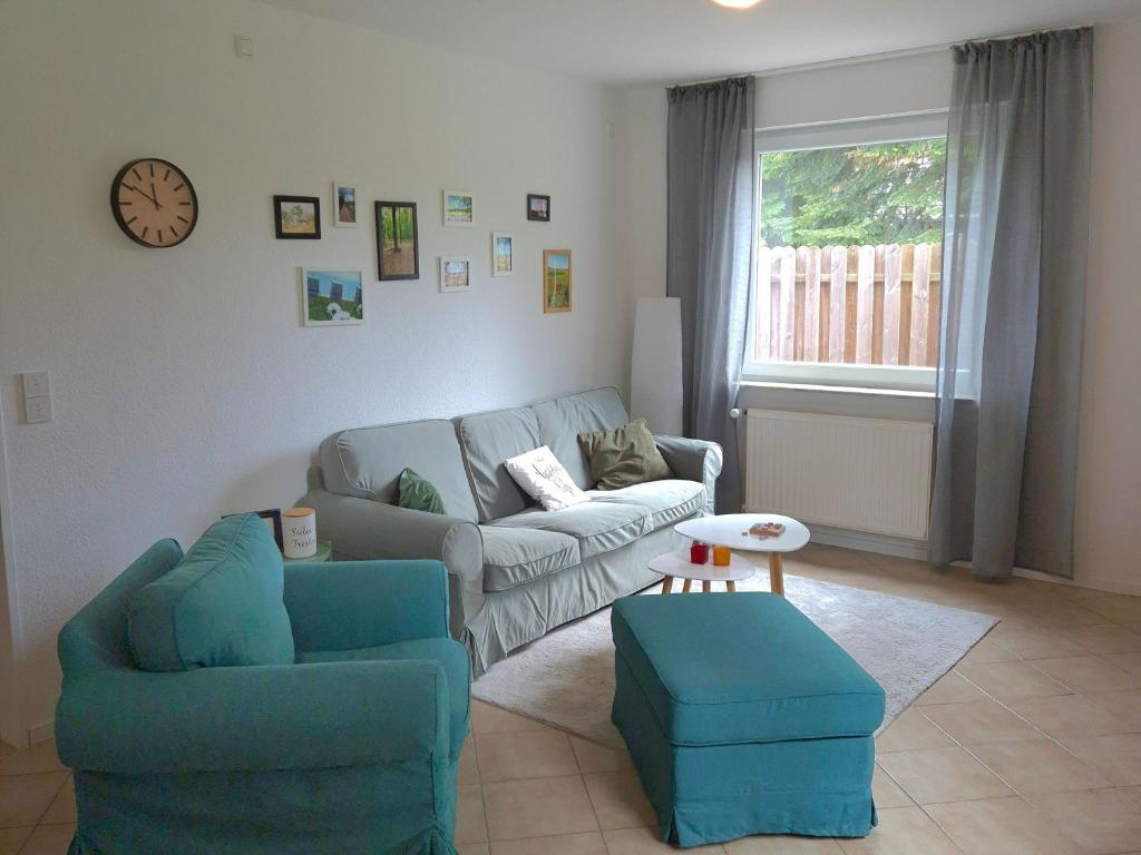 a living room with a couch and chairs and a clock at Ferienwohnung "Haggi" 35672 in Uplengen