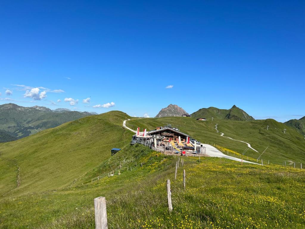 a green hill with a building on the side of it at Panorama Alm in Jochberg