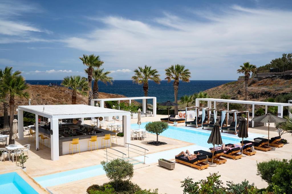 a view of the pool at a resort with palm trees at Aurora Luxury Suites in Imerovigli