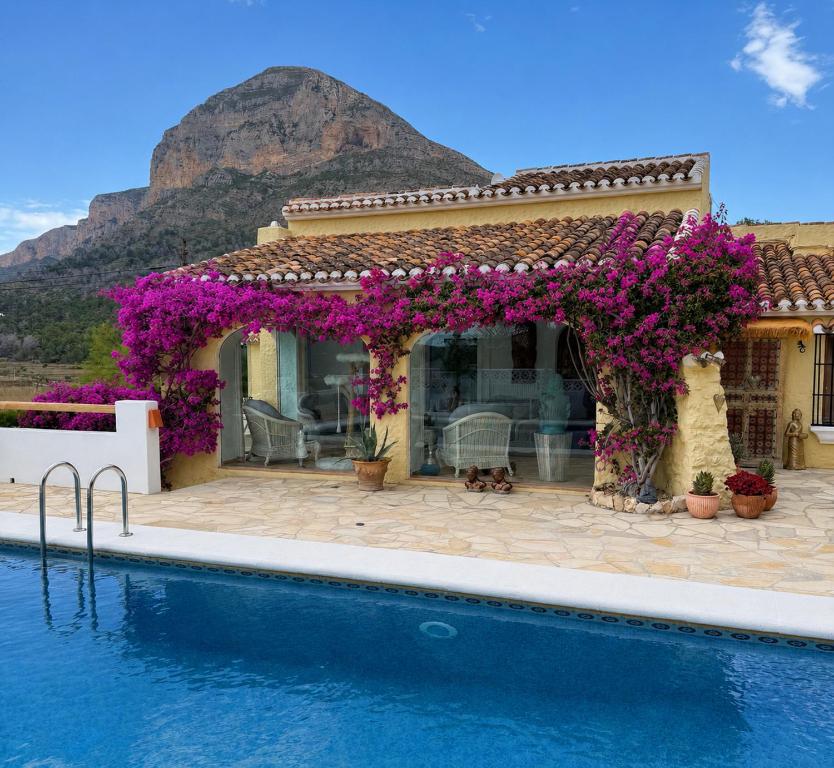 a house with a swimming pool with purple flowers at Villa Mirella in Jávea