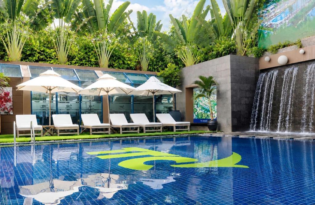 a swimming pool with chairs and a fountain at TTC Hotel Michelia in Nha Trang