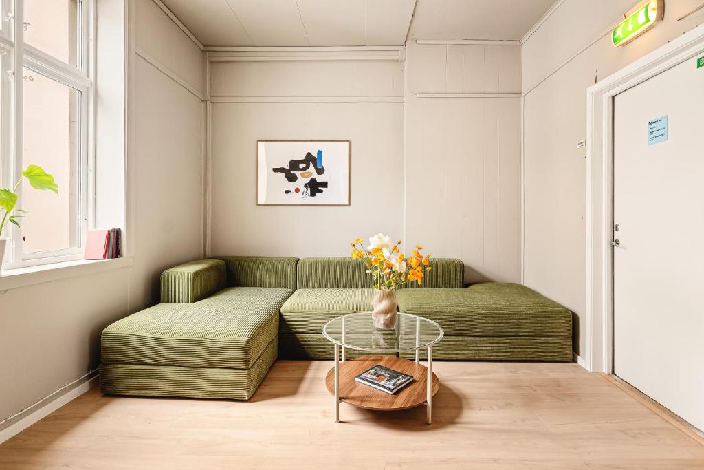 a living room with a green couch and a glass table at Bergen Guesthouse in Bergen
