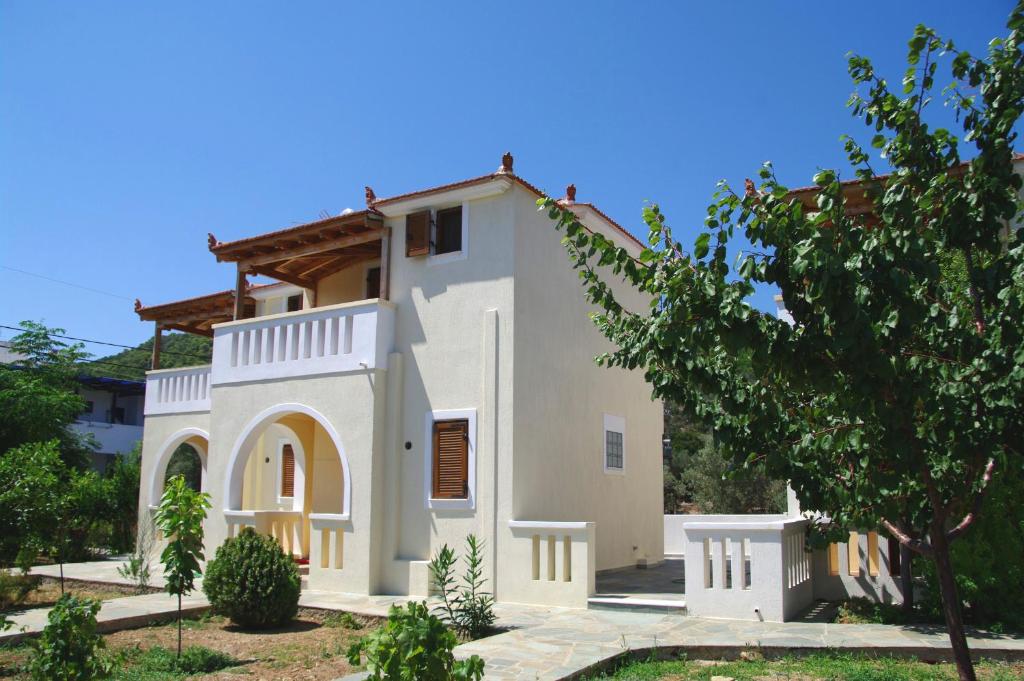 a white house with a tree in front of it at Steni Vala Apartments in Steni Vala Alonissos