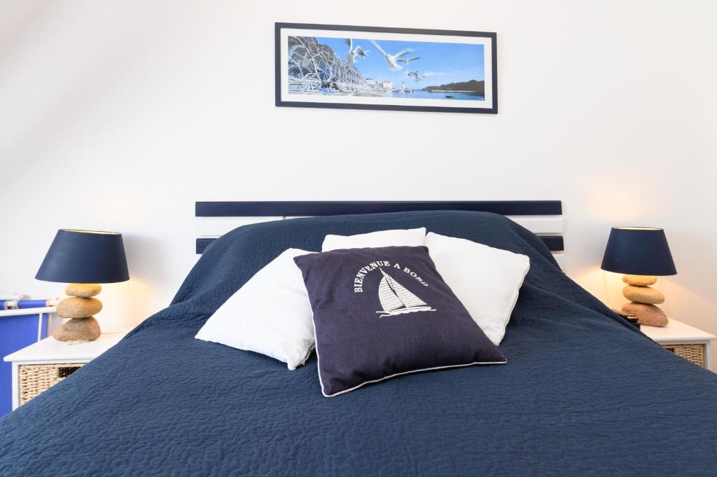a bed with a blue comforter and pillows at Couette et café in Arradon
