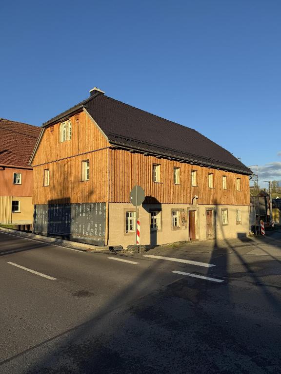 a large wooden building on the side of a street at Glücksschmiede Hennersdorf in Dippoldiswalde