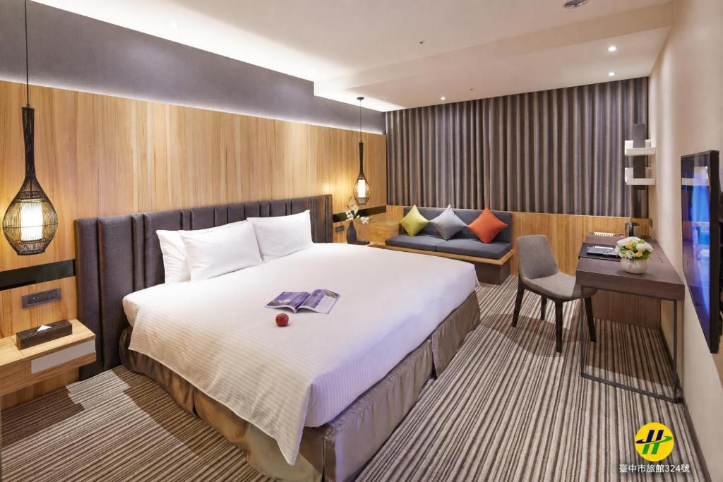 a hotel room with a large bed and a desk at La Vida Hotel in Taichung