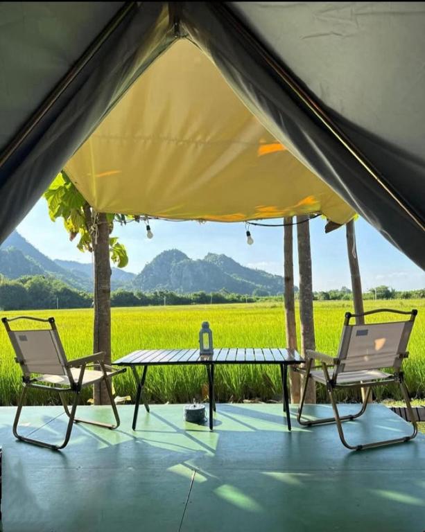 a tent with a table and chairs and a field at Khao Poon Camping in Kanchanaburi City