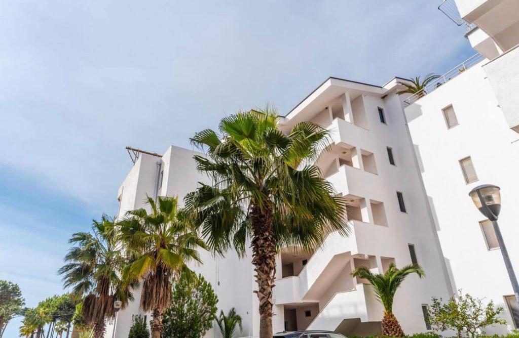 a white building with palm trees in front of it at Lika's Residence in Golem