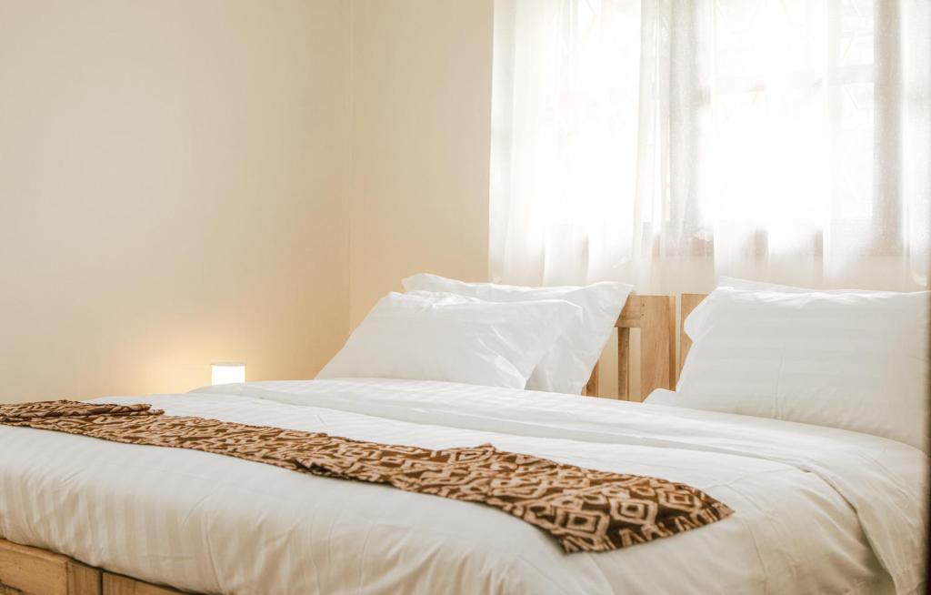 a white bed with a leopard blanket on it at JOSIRE Residence in Entebbe