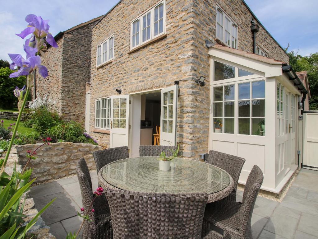 a patio with a glass table in front of a brick house at 5 Shrewsbury Road in Much Wenlock