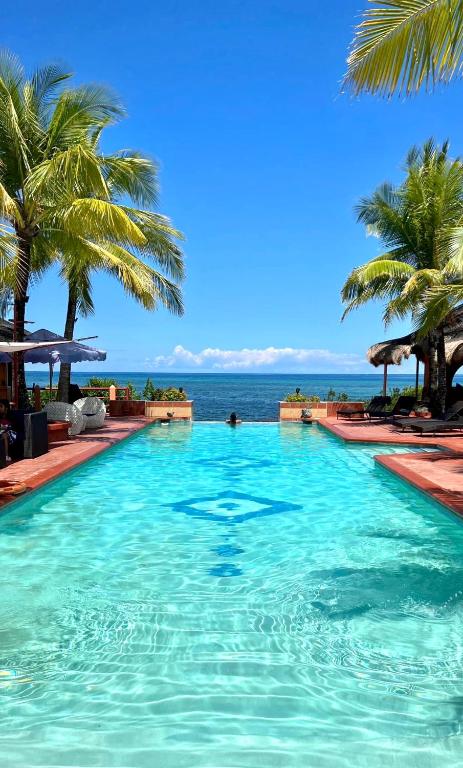 a swimming pool with palm trees and the ocean at M Villa’s Farm Resort in Romblon