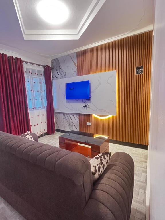 a living room with a couch and a flat screen tv at Soana in Fort Portal