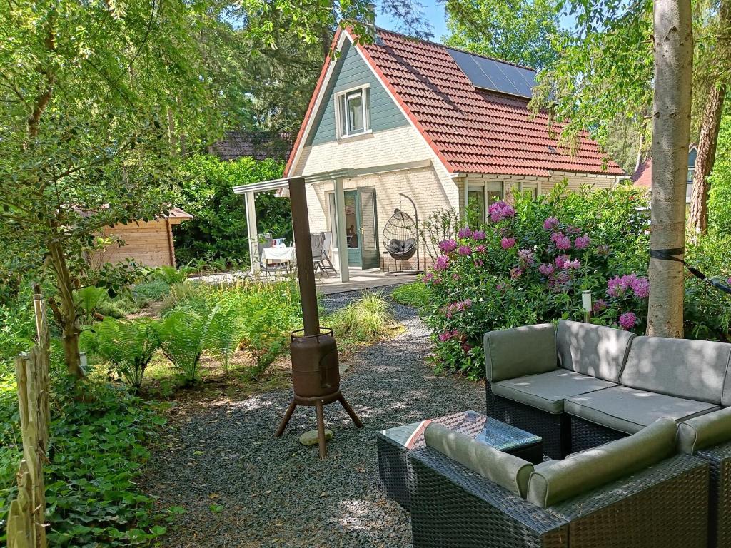 a backyard with a couch and a grill in front of a house at Bosvilla Lochem - Luxe en privacy in de natuur in Lochem