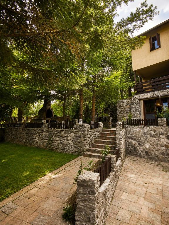 a stone retaining wall with a stone staircase in front of a building at Cabana Brazilor in Câmpina