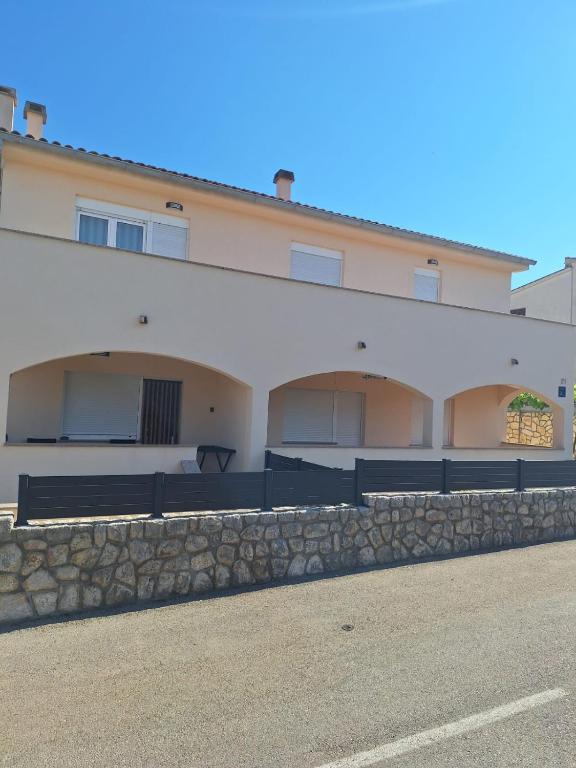 a large white building with a stone wall at Holiday House Snjezana in Krk