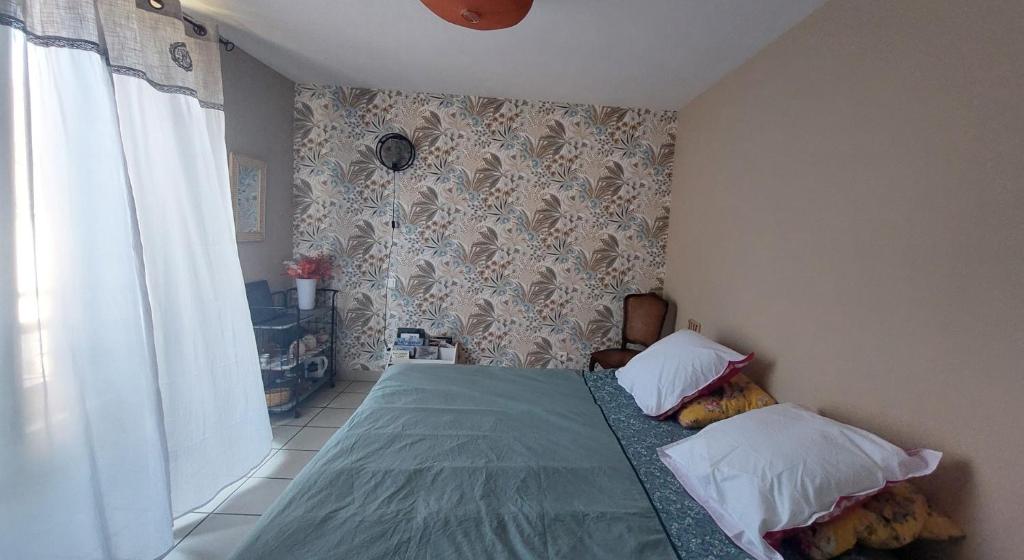 a bedroom with a green bed with two pillows at ROMELLA's ROOM in Saint-Projet