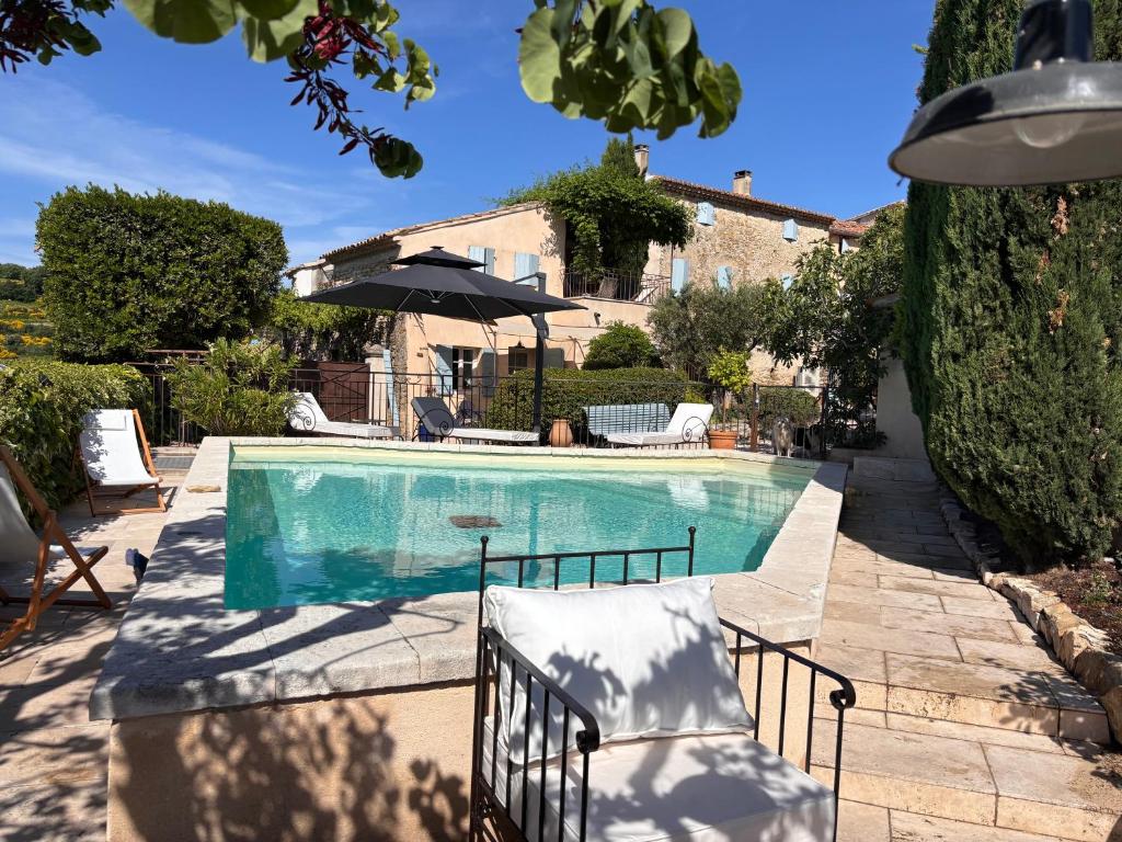 a swimming pool in front of a house at La Bastide des Dentelles in Roaix
