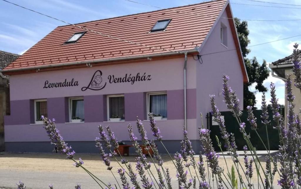 a purple and white building with a red roof at Levendula Vendégház - Bezi in Bezi