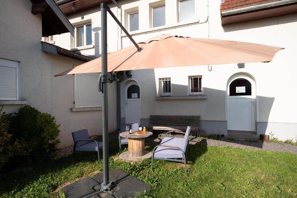 an umbrella in a yard with two chairs and a table at Les Brimbelles in Brû