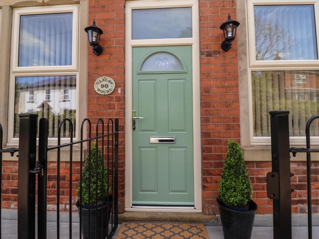 a green door on a brick house with windows at Naseby House in Alfreton