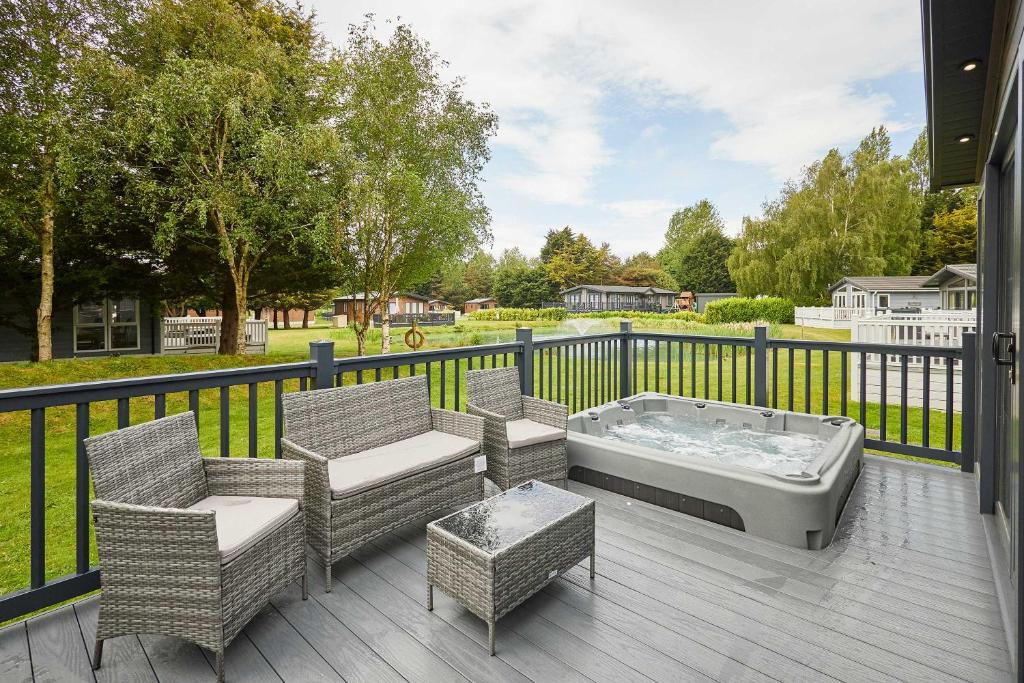 a hot tub and chairs on a deck with a fence at Host & Stay - Rose Lodge in Pocklington