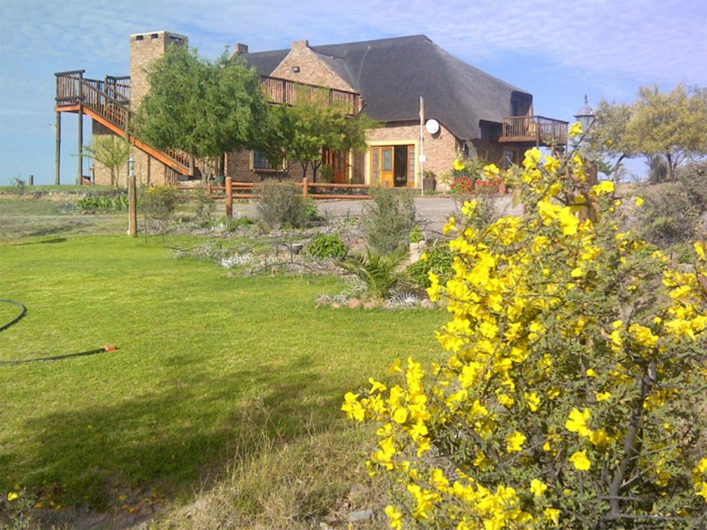 una casa con un patio con flores amarillas en Teri-Lemveli Lodge, en Beaufort West