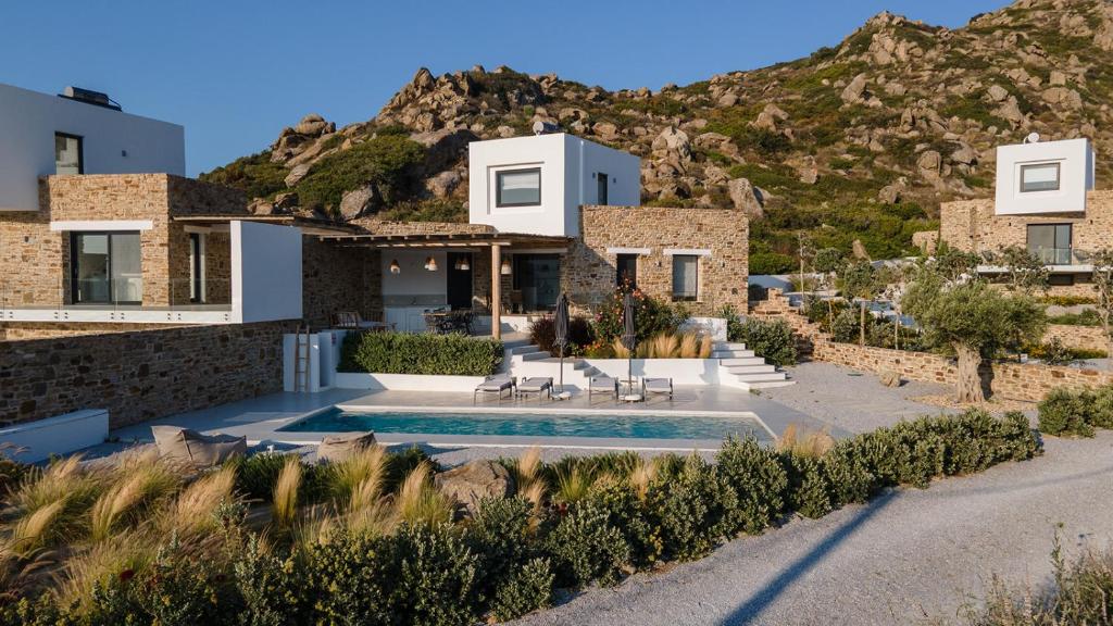 a house with a swimming pool in front of a mountain at Villa Andalusia, Steps from Orkos Beach in Naxos Chora