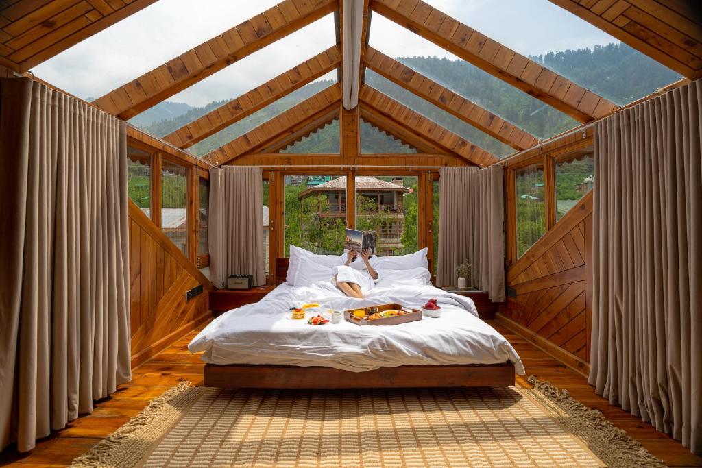 a bedroom with a bed in a room with windows at Padma Villa - Mountain Estate in Manali in Manāli