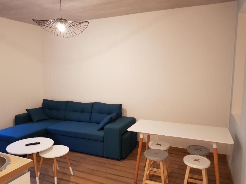 a living room with a blue couch and a table and stools at Gîte climatisé "Baugallo Accordailles" in Saint-Montan