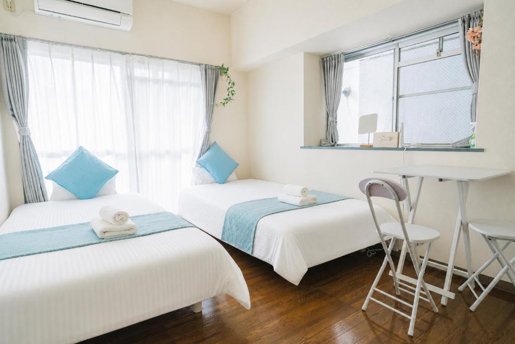 a room with two beds and a desk and a window at MinamiFukuokaHouse in Fukuoka