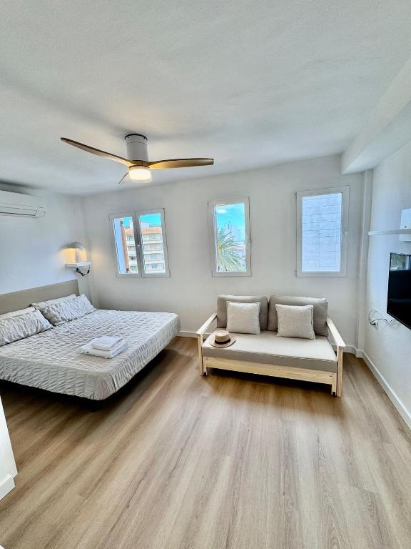a bedroom with a bed and a couch and a ceiling fan at Mediterráneo Suites Port in Jávea