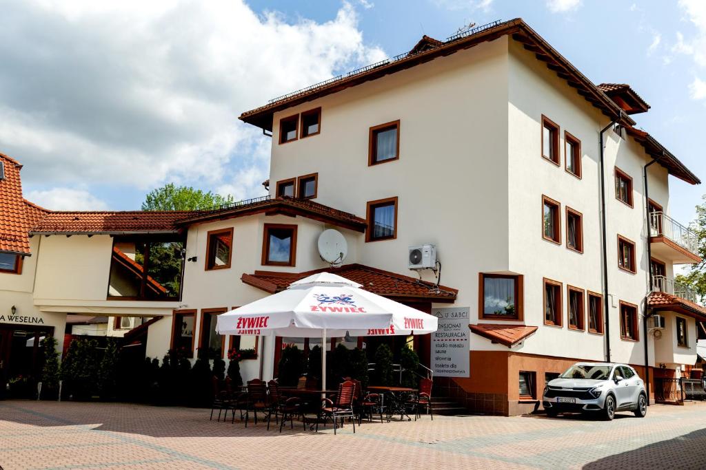 a white building with an umbrella and tables and chairs at Szept Beskidów in Milówka