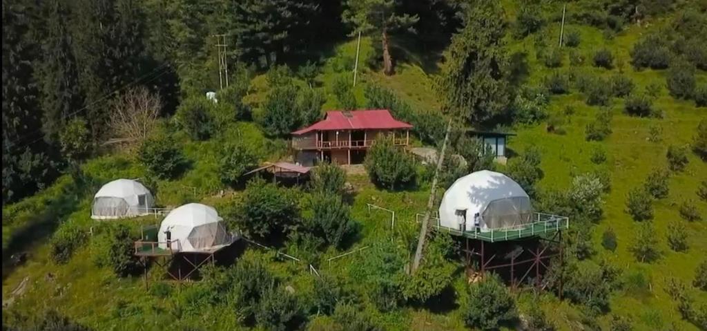 an aerial view of three domes in a field at Earthen Pods in Manāli
