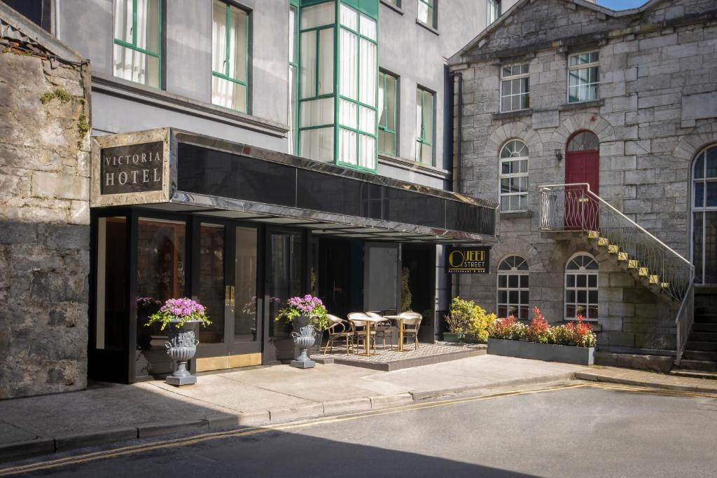 a store with tables and chairs in front of a building at The Victoria Hotel in Galway