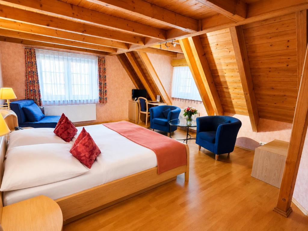a bedroom with a large bed and blue chairs at Hotel Post Jungingen in Jungingen