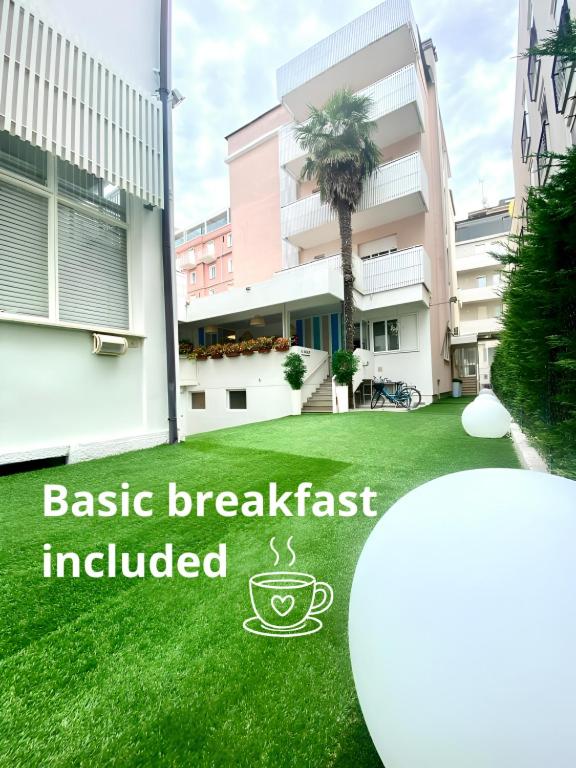a green lawn with a sign that reads basic breakfast included at Hotel Amalfi & Dépendance in Lignano Sabbiadoro