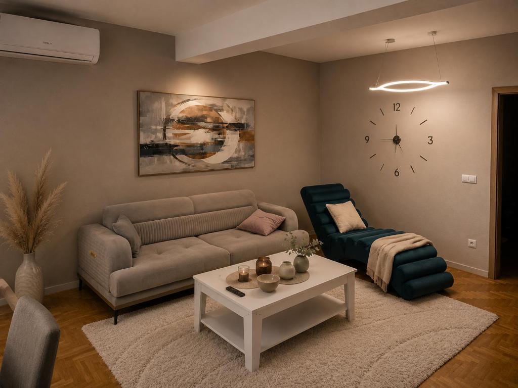 a living room with a couch and a table and a clock at AS Apartment Tetovo in Tetovo