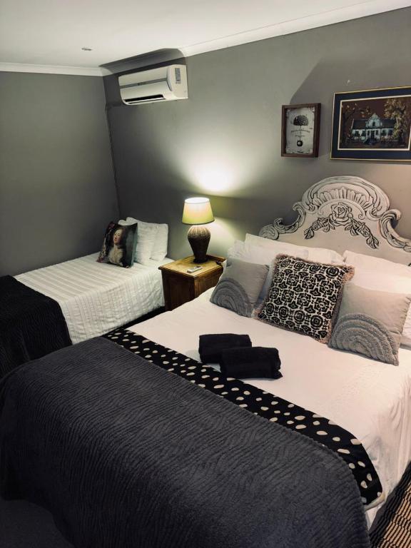 a hotel room with two beds and a lamp at La Grace Guestrooms in Kroonstad