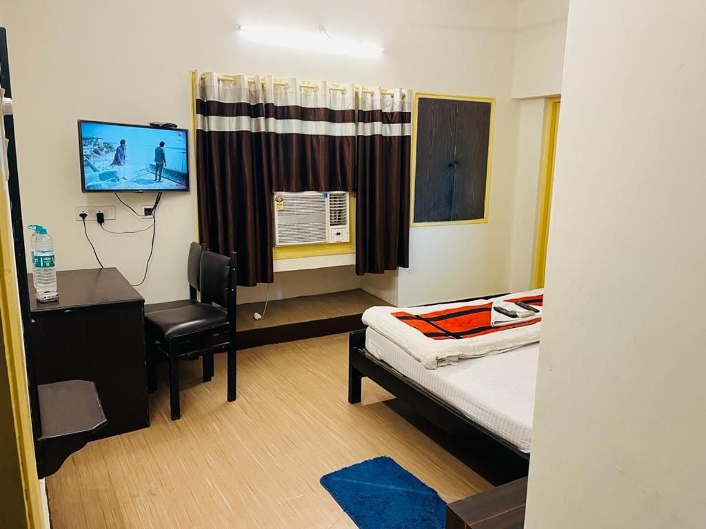 a hospital room with a bed and a desk and a chair at Hotel Penguin International in Kolkata