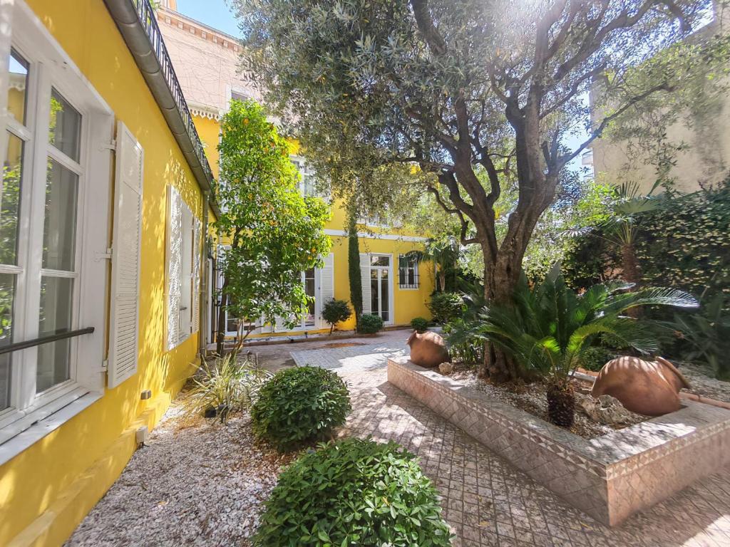 a yellow house with a tree in a courtyard at La Maison Cannoise in Cannes