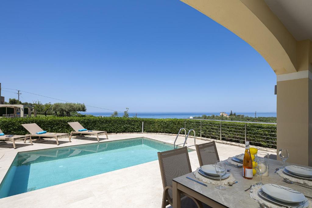 a patio with a table and a swimming pool at Carme Villas in Adelianos Kampos