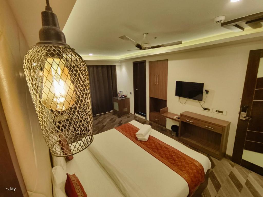 a hotel room with a large bed and a chandelier at THE TRIUMPH Hotel in Varanasi